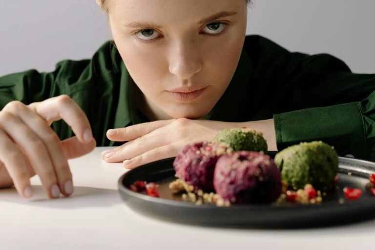 A woman intently observing traditional Georgian pkhali on a plate, showcasing beetroot and spinach varieties.